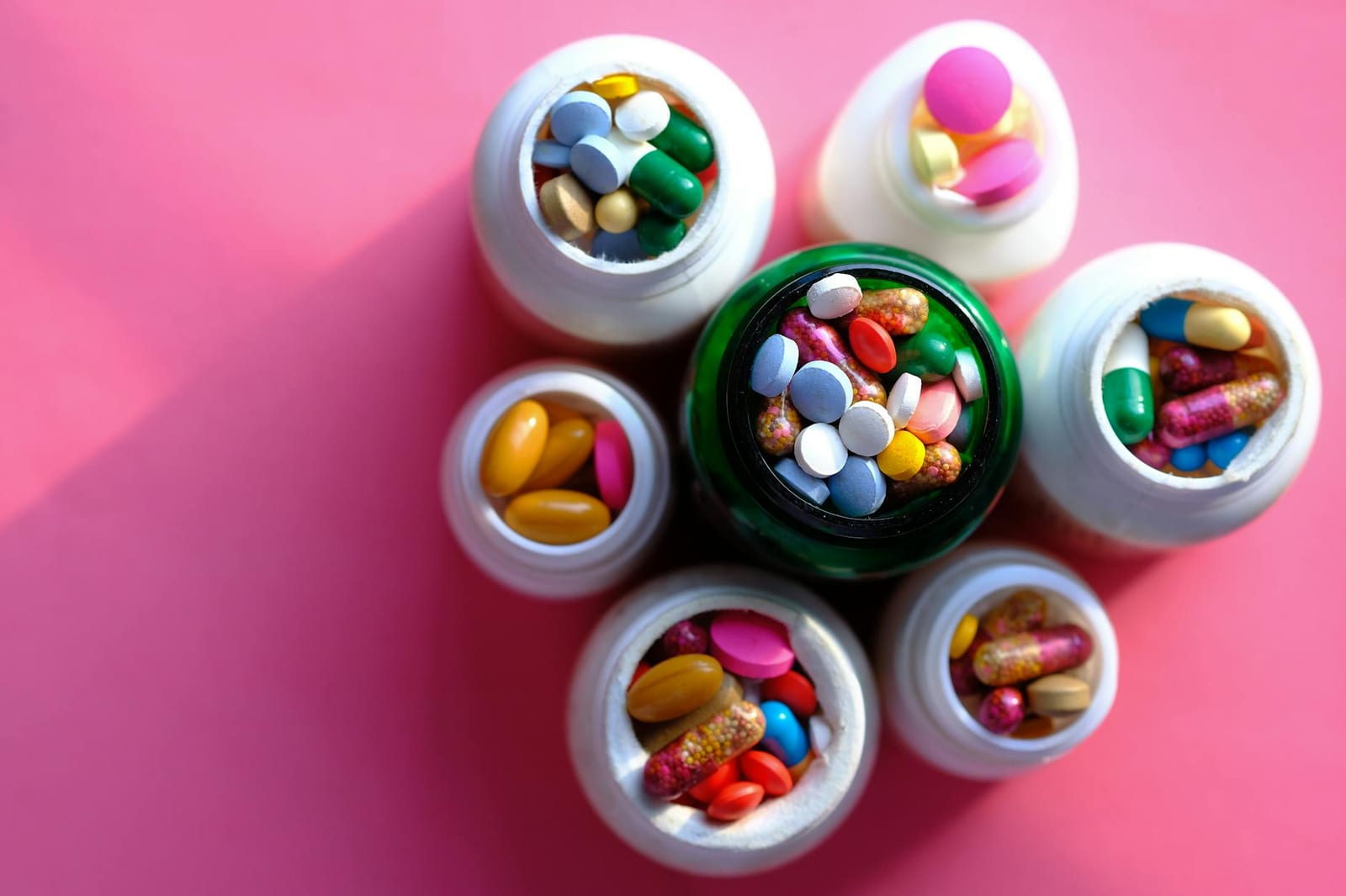 Assorted medication tablets and capsules in open pharmacy bottles